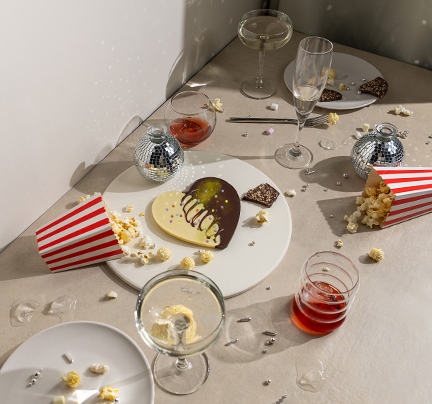 Auf einem Tisch sind Getränke, ein Kreolade-Herz und Popcorn verteilt